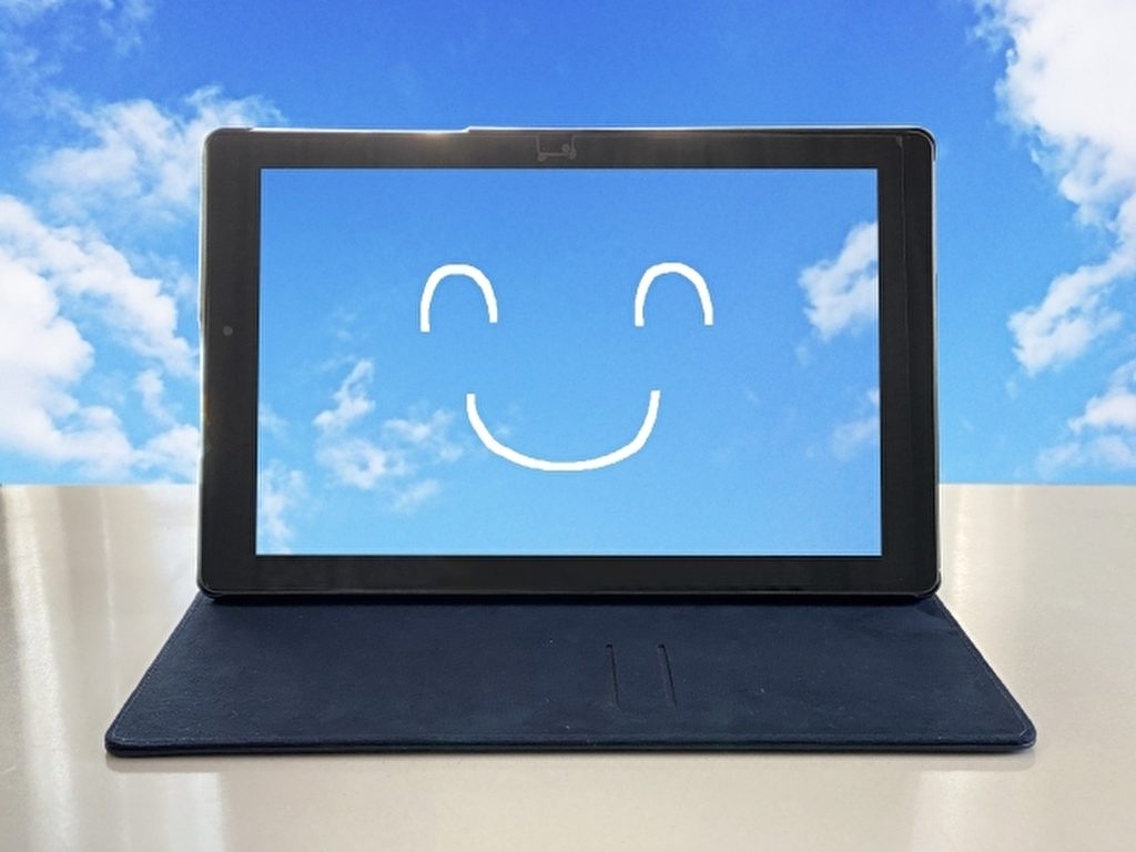 黒いノートパソコンに青空の画面、白い線で笑顔のイラストが書かれている