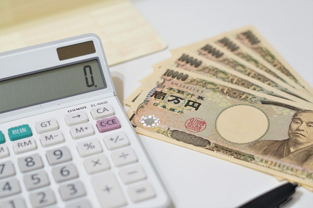 数枚の一万円札と0が表示された電卓