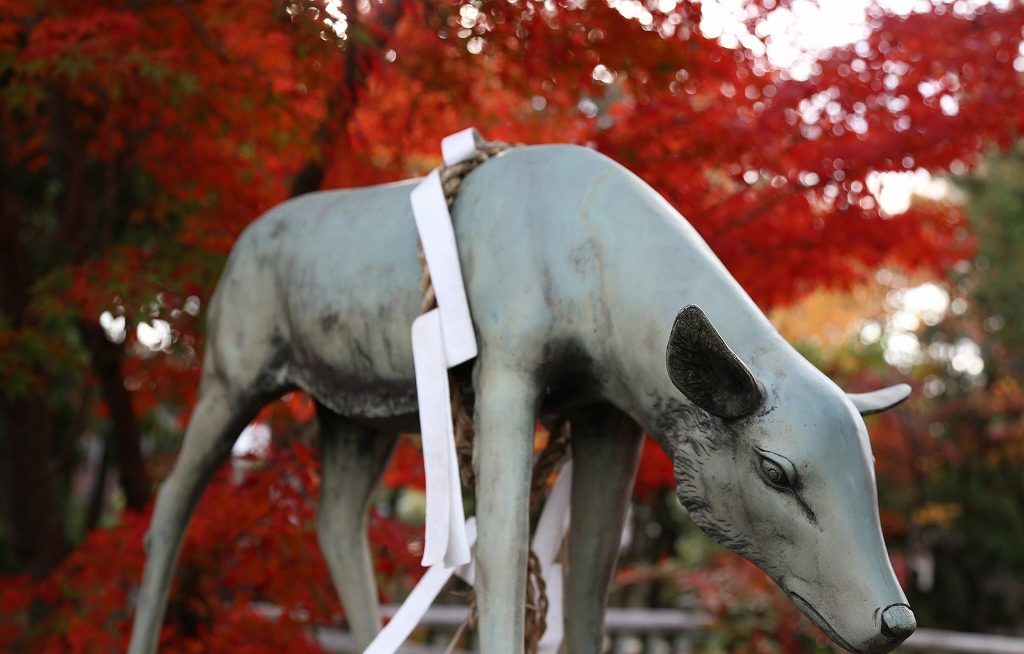 立木神社動物の銅像と背景に赤い紅葉